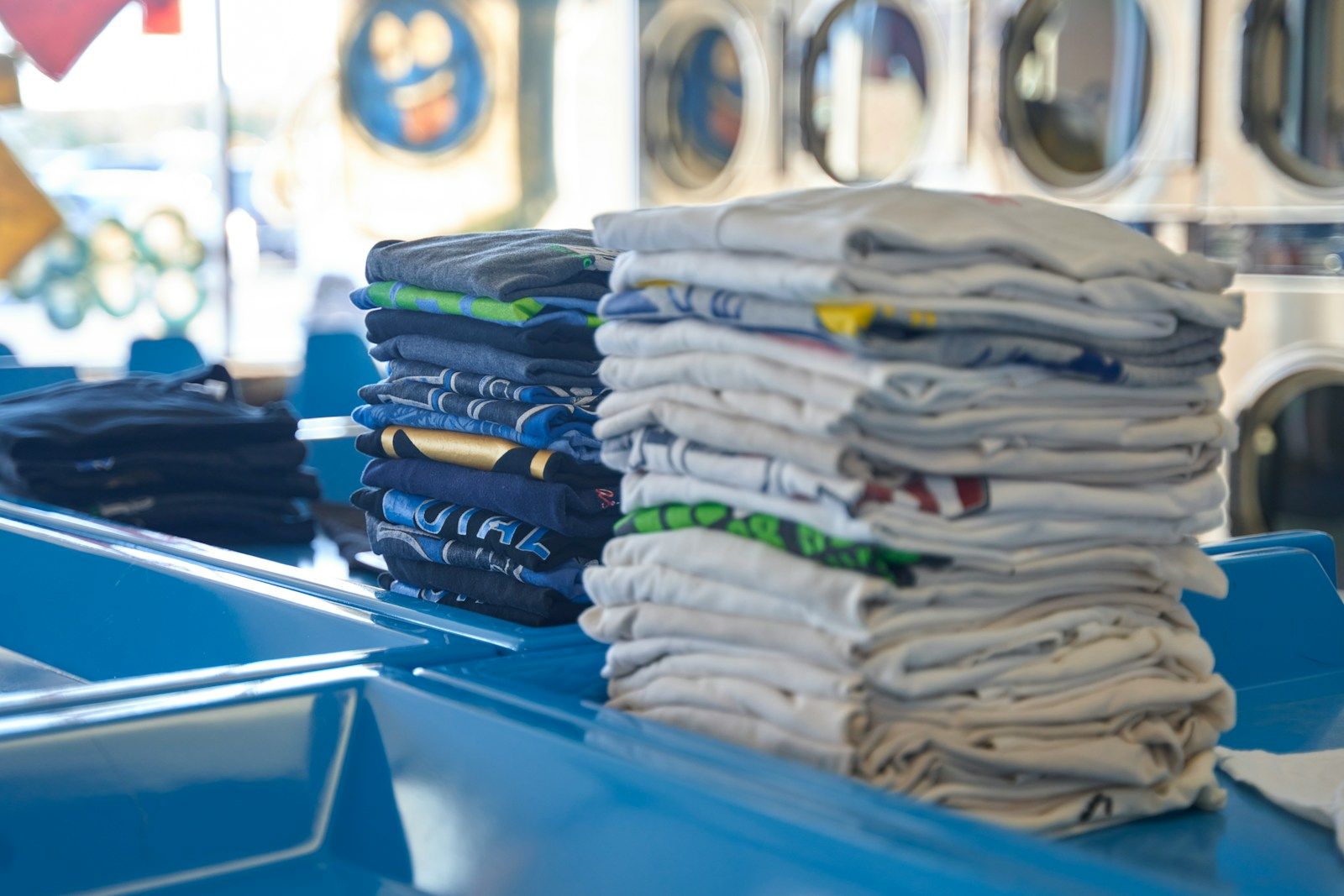Neat stacks of freshly washed and folded t-shirts on a laundry counter
